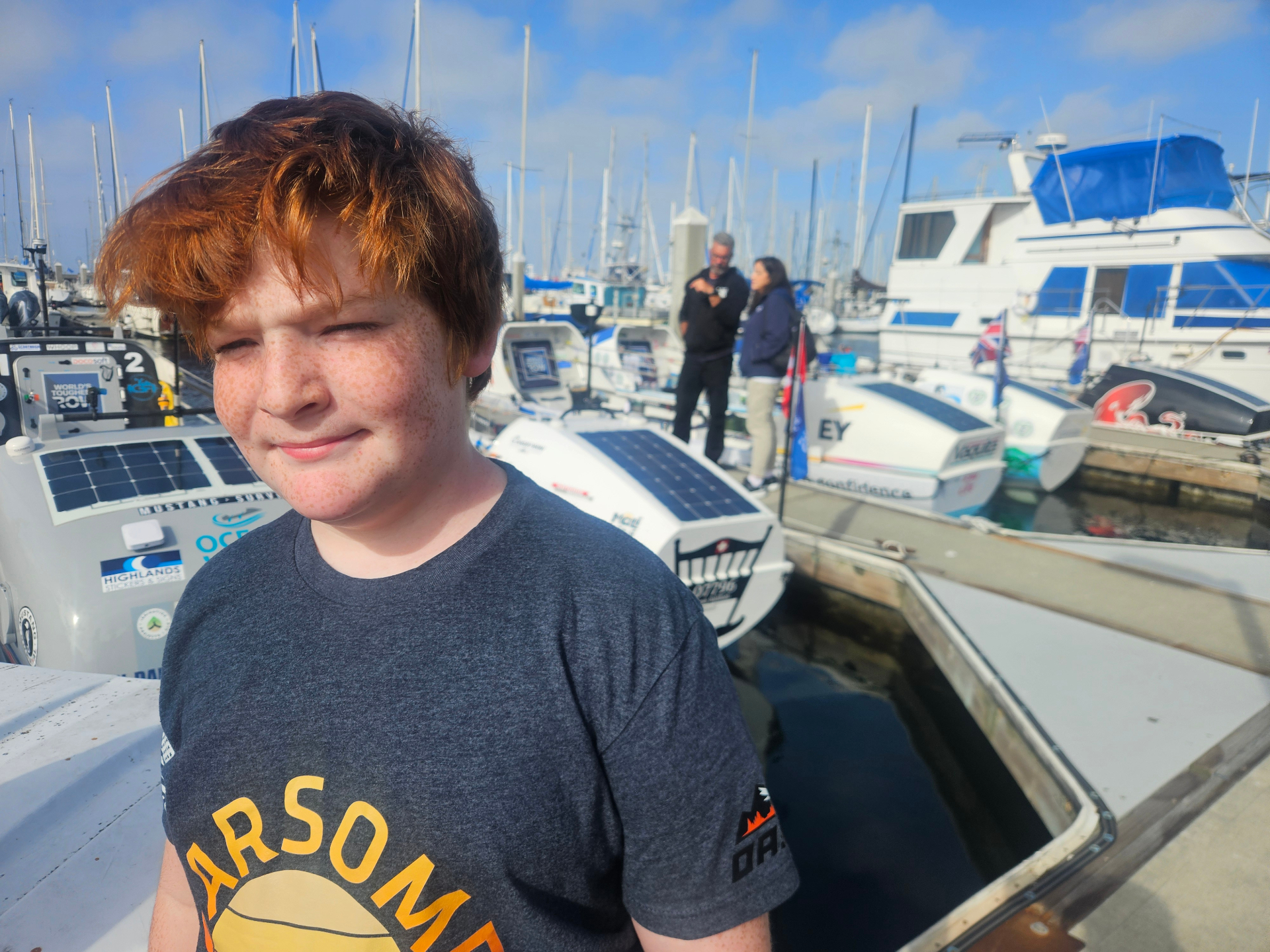 Aiden at the dock in front of ocean rowing boats